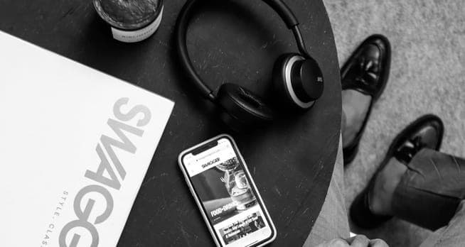 XX99 Mark II headphones resting on a coffee table beside a phone and a magazine.