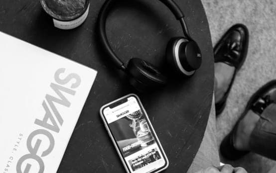 XX99 Mark II headphones resting on a coffee table beside a phone and a magazine.