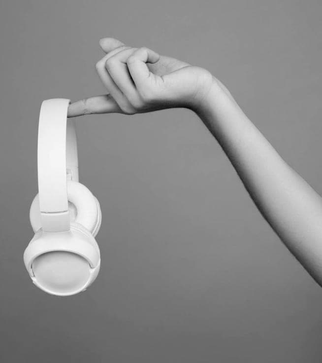 An arm holding on to XX59 headphones by the index finger.