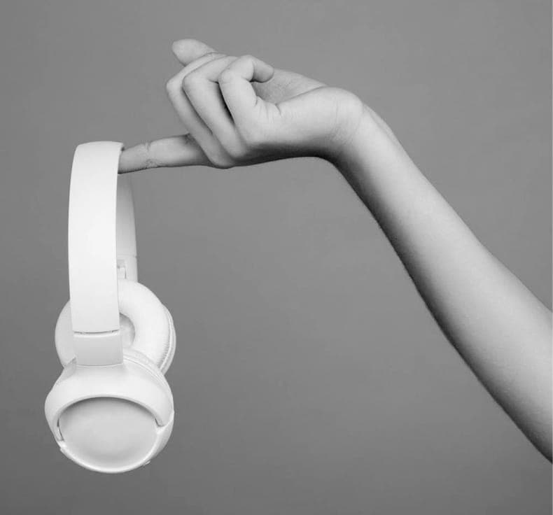 An arm holding on to XX59 headphones by the index finger.